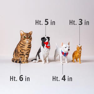 May include: Four animal figurines: a tabby cat (6 in), a black and white dog (5 in), a white dog (4 in), and an orange cat (3 in). The dogs have accessories. Text indicates the height of each figurine.