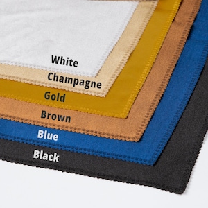 May include: A stack of fabric swatches in various colors, including white, champagne, gold, brown, blue, and black. Each swatch has a decorative, scalloped edge. The names of the colors are printed on the fabric.
