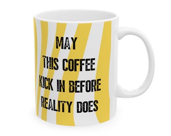 May include: White ceramic coffee mug with a yellow and white striped pattern. The mug features the text "MAY THIS COFFEE KICK IN BEFORE REALITY DOES" in black lettering. The mug has a white handle.
