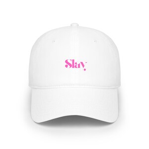 Op de afbeelding: Witte baseballpet met een gebogen klep. De pet heeft het woord "Slay" in roze, gecentreerd op de voorkant. De hoed is gemaakt van een gladde stof en heeft een gestructureerd ontwerp, geschikt voor casual wear.