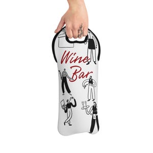 Op de afbeelding: Witte wijnfleshouder met een zwarte handgreep en rand. De woorden "Wine Bar" zijn in rood script geschreven. De houder heeft zwart-witte illustraties van mensen in een barsituatie.
