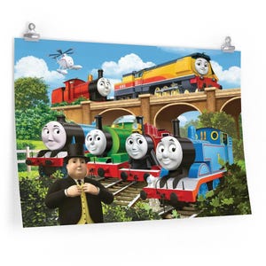 May include: A colorful poster featuring Thomas the Tank Engine and friends. The image shows several cartoon trains, including a red one, a green one, and a blue one, along with a helicopter and a man in a suit. The background includes a bridge and blue sky.