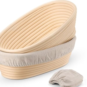 以下が含まれることがあります： リネンライナー付きの、2つの楕円形の明るい色の木製パン発酵バスケット。バスケットは積み重ねられており、下部に別のリネンカバーが付いています。バスケットはリブのデザインです。