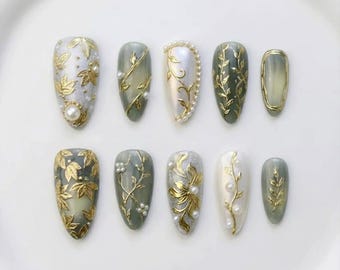 Groene pers op nagels met bladgoud en parelaccenten, amandelbotanische stijl