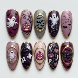 May include: A set of ten almond-shaped press-on nails featuring Halloween-themed designs. The nails display purple, pink, and gray backgrounds with hand-painted illustrations of white ghosts, orange jack-o'-lanterns, black bats, and bare trees.