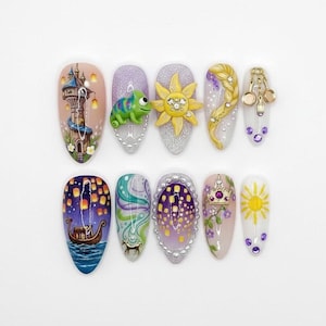 May include: A collection of ten long, oval acrylic nails, each with a unique design. Designs include a tower, a chameleon, a sun, a braid, a boat, and a crown, in bright colours. Some nails have 3D decorations.