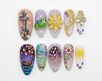 Puede incluir: Un conjunto de diez uñas acrílicas largas y ovaladas con varios diseños. Los diseños incluyen una torre, un camaleón, un sol, una trenza, un barco y una corona, todos en colores vibrantes. Algunas uñas presentan adornos en 3D.