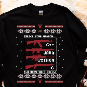 May include: Black sweatshirt with a festive design. The text reads "SELECT YOUR WEAPON..." followed by C++, JAVA, PYTHON, and C, with the phrase "AND SHOW YOUR SKILLS." The design includes red weapon graphics and snowflake patterns.