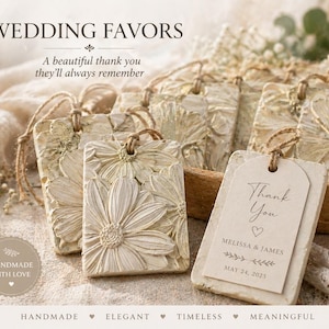 Puede incluir: Etiquetas de recuerdo de boda de color crema con diseños de flores de margarita y las palabras "Thank You". Las etiquetas están atadas con hilo y presentan los nombres Melissa & James y la fecha 24 de mayo de 2025. Las palabras "Wedding Favors" están en la parte superior.