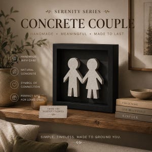 Peut inclure: Un cadre carré noir de type boîte contenant deux figurines de couple en béton gris clair se tenant par la main. Le texte sur le cadre indique SERENITY SERIES CONCRETE COUPLE HANDMADE MEANINGFUL MADE TO LAST. Une petite carte indique FROM THE SERENITY SERIES.
