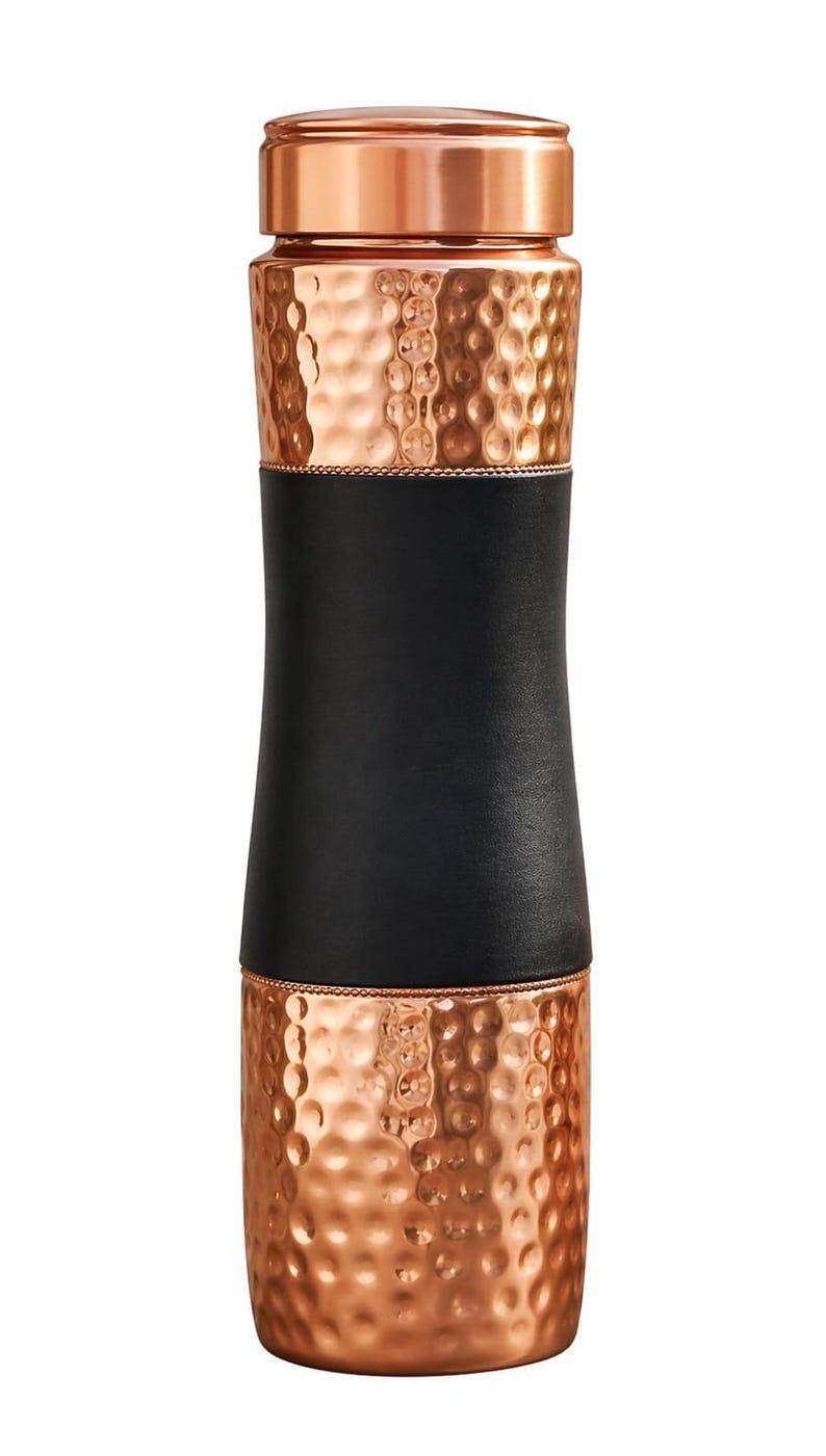 May include: A copper-colored water bottle with a hammered texture. The bottle has a black leather band around the middle. The top and bottom sections are copper, and the lid is also copper-colored.