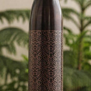 May include: A copper-coloured water bottle with a decorative floral pattern. The bottle has a dark cap and base, and the patterned section is in a lighter copper hue. The bottle is designed to keep beverages cold or hot.