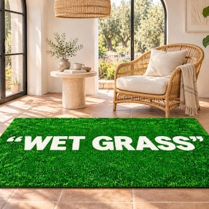Peut inclure: Un tapis rectangulaire présentant une texture d'herbe artificielle vert vif. Le tapis affiche le texte "WET GRASS" en grandes lettres capitales blanches et grasses centrées au milieu, créant un contraste marqué avec la surface verte.
