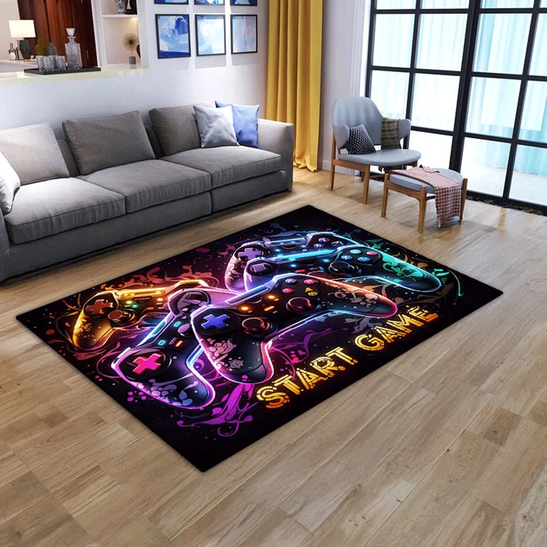 Puede incluir: Una alfombra rectangular con un gr&aacute;fico vibrante de colores ne&oacute;n de dos mandos de videojuegos sobre un fondo negro. El dise&ntilde;o incluye patrones de luz en espiral y el texto START GAME en letras amarillas brillantes y negritas.