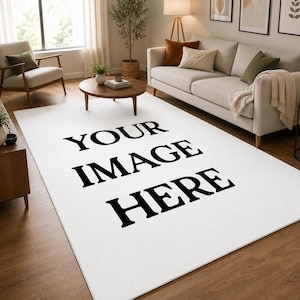 May include: A large, rectangular white rug with the text "YOUR IMAGE HERE" in bold black letters. The rug is in a living room setting, with a sofa, chairs, and a coffee table visible in the background. The room has hardwood floors and natural light.