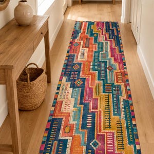 May include: A long rectangular runner rug featuring a vibrant geometric pattern with blocks of deep blue, bright orange, magenta, and mustard yellow. The design incorporates intricate linear details and small diamond shapes across the surface.