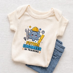 May include: Cream-colored baby onesie with a colorful graphic of a gear wearing a yellow hard hat, surrounded by tools and stars. The text "FUTURE ENGINEER IN TRAINING" is printed below the graphic. Blue denim jeans are visible.