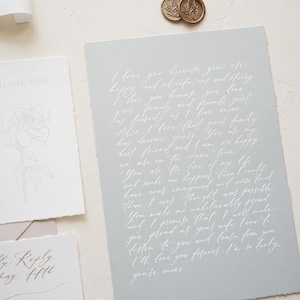 May include: A collection of stationery items, including a large gray paper with handwritten text, a thank you card with a floral design, and a reply card. Two gold wax seals are in the top right corner.
