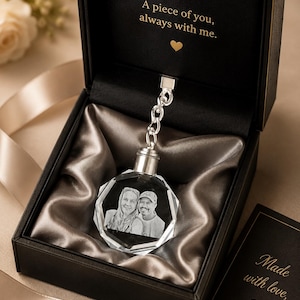 May include: A faceted crystal keychain featuring a laser-etched portrait of two people, attached to a silver-toned chain. It is presented in a black gift box with the text A piece of you, always with me. and a small heart icon printed inside.
