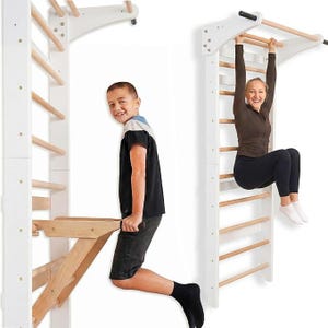 May include: A wall-mounted wooden stall bar unit featuring white vertical side panels and natural light-colored horizontal rungs. The structure includes a top pull-up bar and a detachable wooden dip station attachment for exercise.