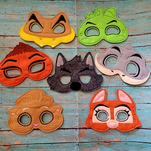 May include: A collection of seven felt animal masks in various colors, including brown, orange, green, gray, and tan. Each mask features eye holes and is designed with animal features like ears and snouts. The masks are arranged on a blue wooden surface.
