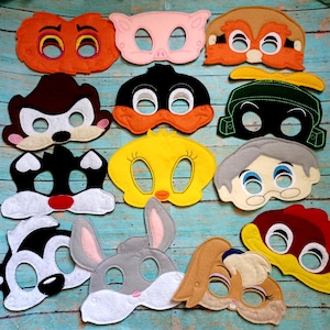 May include: A collection of twelve felt character masks featuring various cartoon designs, including animals and human figures with stitched details, eye cutouts, and vibrant colors like orange, yellow, black, white, grey, and brown.