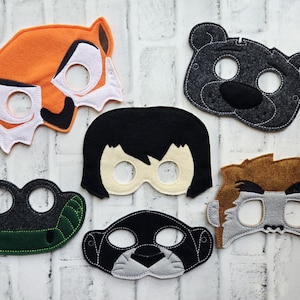 May include: A collection of felt animal masks in various colors. The masks include a fox, bear, human, crocodile, panther, and lion. Each mask has eye holes and is designed with detailed features.