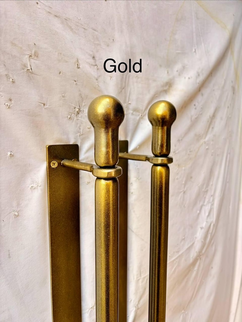 K&ouml;nnte beinhalten: Ein goldfarbenes T&uuml;rgriff-Set aus Metall mit zwei vertikalen zylindrischen Stangen und abgerundeten, kugelf&ouml;rmigen Endst&uuml;cken an der Oberseite. Jede Stange ist mit einer sichtbaren Schraube an einer rechteckigen Montageplatte befestigt. Der Text Gold steht dar&uuml;ber.