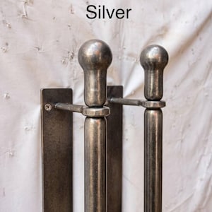 K&ouml;nnte beinhalten: Zwei silberfarbene T&uuml;rgriffe aus Metall mit glattem, zylindrischem Design und kugelf&ouml;rmigen Endst&uuml;cken. Jeder Griff ist an einer rechteckigen Metallmontageplatte mit einer sichtbaren Schraube befestigt. Das Wort Silver steht dar&uuml;ber.