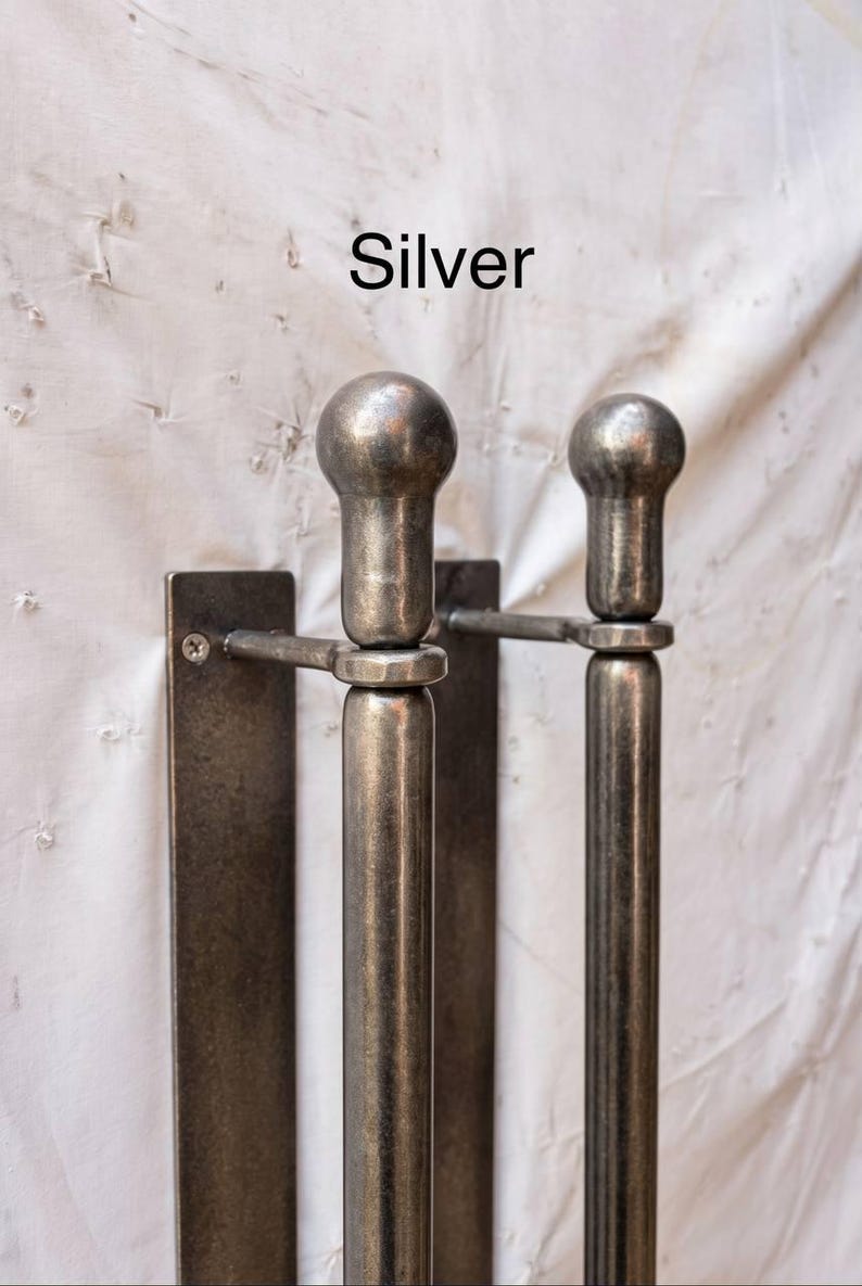 K&ouml;nnte beinhalten: Zwei silberfarbene T&uuml;rgriffe aus Metall mit glattem, zylindrischem Design und kugelf&ouml;rmigen Endst&uuml;cken. Jeder Griff ist an einer rechteckigen Metallmontageplatte mit einer sichtbaren Schraube befestigt. Das Wort Silver steht dar&uuml;ber.