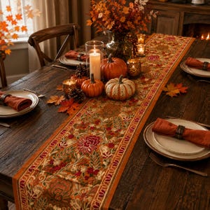 May include: A long, rectangular table runner featuring an intricate, multi-colored floral embroidery pattern in shades of orange, red, green, and cream, centered on a dark wooden dining table with pumpkins, candles, and place settings.