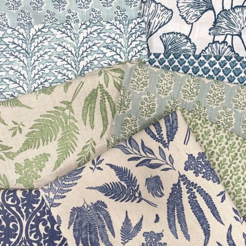 Op de afbeelding: Assortiment van stofstalen met verschillende bloemen- en bladpatronen in tinten blauw, groen en wit. De stoffen zijn in een gelaagde weergave gerangschikt, waardoor de verschillende texturen en ontwerpen worden getoond.