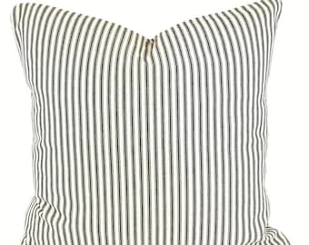 May include: A white pillow with black stripes. The pillow is made of a soft, woven fabric and has a zipper closure.