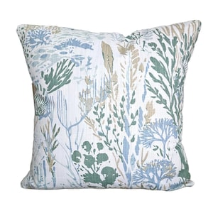 May include: Square decorative pillow with a botanical print. The pillow features a white background with a pattern of green, blue, and tan plant-like shapes. The pillow is a square shape.