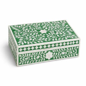 May include: A rectangular box featuring a vibrant green surface with intricate white floral and leaf patterns. The lid displays a central star motif, while the sides are decorated with a repeating quatrefoil border and floral vine designs.