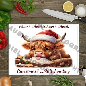 May include: A white cutting board with a cartoon Highland cow wearing a Santa hat, surrounded by flour, rolling pin, and spices. Text reads "Flour? Check. Chaos? Check. Christmas? ... Still Loading."