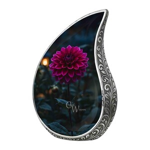 Op de afbeelding: Een traanvormige gedenkhanger met een gedetailleerde zilverkleurige rand. De hanger toont een close-up van een diep magenta dahlia bloem tegen een donkere achtergrond. De tekst "Crafted Whispers" is zichtbaar.