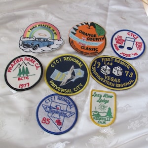Pode incluir: Nove patches bordados com vários desenhos e textos. Os patches são circulares e apresentam uma variedade de cores, incluindo azul, vermelho, verde, amarelo e branco. O texto nos patches inclui "CTCI Regional", "First Biennial", "Lazy River Lodge", "Frazier Park CA", "Orange County Classic", "Do You Know The Way To San Jose '76", e "I Bird Heaven In '67".