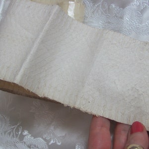 May include: A close-up of a white, textured, paper scroll. The scroll is folded and has a rough, uneven edge.