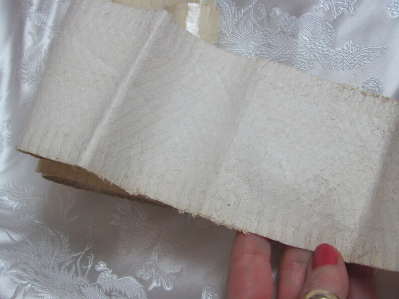 May include: A close-up of a white, textured, paper scroll. The scroll is folded and has a rough, uneven edge.