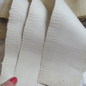 May include: Four sheets of white, textured paper, folded and stacked on top of each other. The paper has a slightly rough, uneven surface.