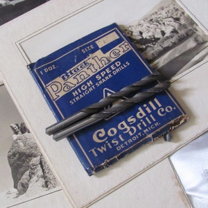 May include: A blue and white box of Black Panther High Speed Straight Shank Drills by Cogsdill Twist Drill Co. Detroit, Mich. The box contains two drill bits.