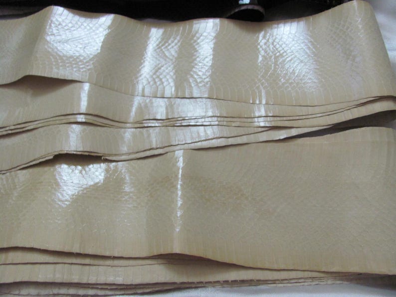 May include: A stack of beige leather strips with a textured surface. The leather has a subtle sheen and appears to be smooth and supple.