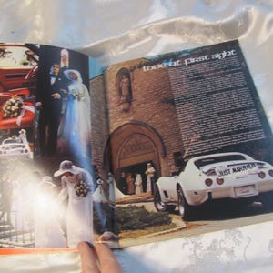 May include: A magazine spread featuring wedding photos and a white Corvette. The car has a "Just Married" sign on the back. The interior of the car is red. The text "love at first sight" is visible.