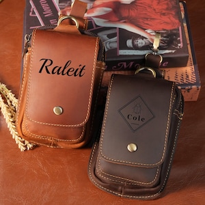 Puede incluir: Dos fundas de cuero para cinturón con herrajes metálicos y cierres a presión. La funda izquierda es de color marrón claro con el texto Raleit impreso en la solapa. La funda derecha es de color marrón oscuro con un gráfico de diamante y el texto Cole.