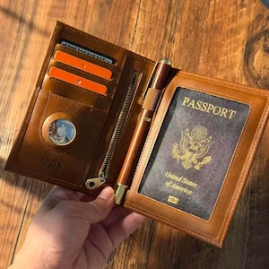 May include: A white ceramic mug with a black handle and the text "But First, Coffee" in a bold, black font. The mug is set against a blurred background, highlighting its clean design.
