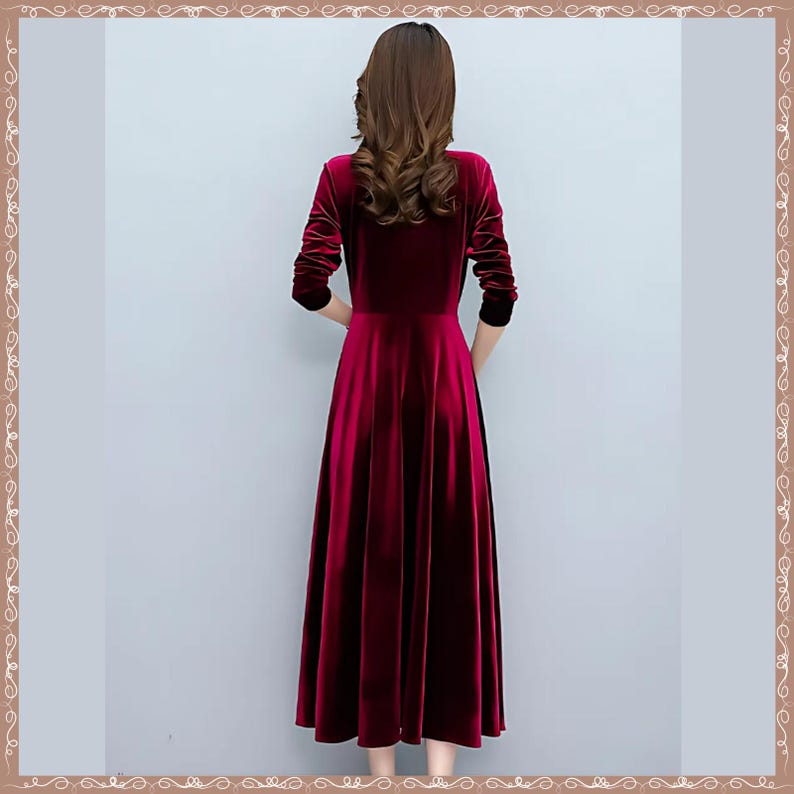 May include: A long, flowing, burgundy velvet dress with long sleeves. The dress has a round neckline and a flared skirt. The sleeves end at the wrists with a black trim. The dress is a solid color and appears to be made of a soft, luxurious fabric.