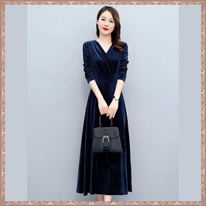May include: A long, navy blue velvet dress with a V-neck and long sleeves. The dress is paired with a small black handbag. The woman is wearing a watch on her left wrist.