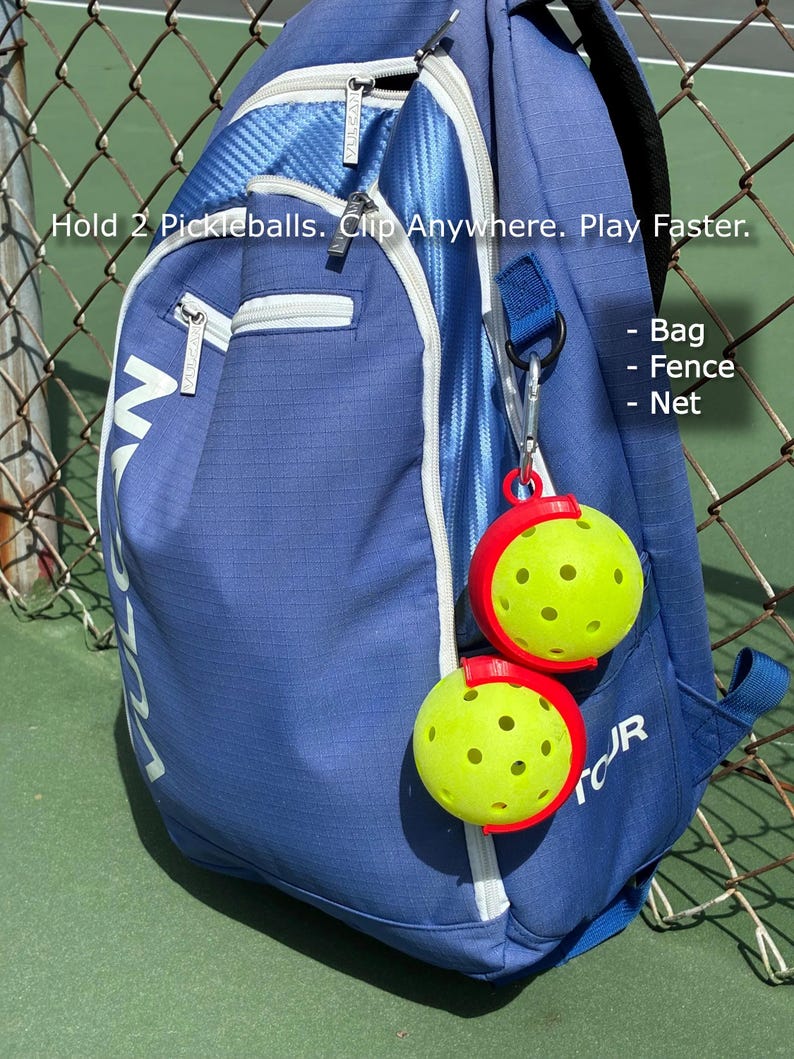 Puede incluir: Una mochila azul con cremalleras blancas y la palabra "VULCAN" impresa. Dos pelotas de pickleball amarillas se sujetan con clips rojos sujetos a la bolsa. El texto "Hold 2 Pickleballs. Clip Anywhere. Play Faster." es visible.