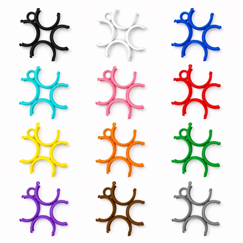 May include: A selection of star-shaped silicone trivets in a range of colours: black, white, blue, turquoise, pink, red, yellow, orange, green, purple, brown, and grey. Each trivet has a central ring and six curved arms.
